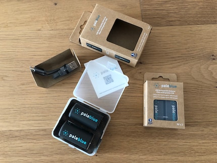 Die Hartplastikbox mit den Batterien und dem Kabel zum Laden verpackt Pale Blue in einem Karton.