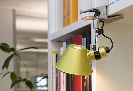 De Tolomeo Pinza Micro is als een spinaap op de plank geklemd en accentueert de boekenkast.