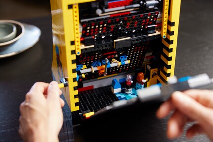 De achterkant van de Lego set is afneembaar. Je kunt niet alleen het spelmechanisme bekijken, maar er staat je ook een kleine verrassing te wachten: een mini Lego-mannetje verdiept zich in zijn Pac-Man game.