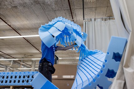 Once the machine has cut out the patterns, an employee takes the leftover material away.