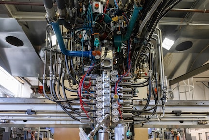A machine that could’ve been designed by H.R. Giger sprays the base for the foam «cake» onto a conveyor belt.