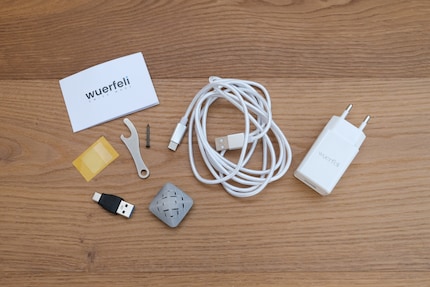 De «Wuerfeli» wordt geleverd met de kabel of de adapter. Hiermee kun je de sensor rechtstreeks in een stopcontact plaatsen met behulp van een USB-voeding. Er zijn plakstippen en een spijker om hem aan de muur of meubels te bevestigen.