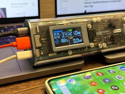 Two MacBooks and a smartphone are charged at the same time.