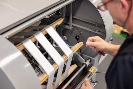 Een machine legt de draden netjes op een rij.