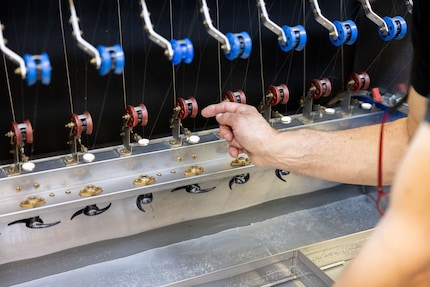 Een mens rijgt de cocons, een machine rolt ze helemaal af.