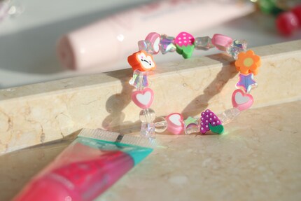 Den Gloss von Essence habe ich mit einem perlenbeladenen Gummiband verziert. So lässt er sich auch am Handgelenk tragen.