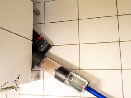 De gelede natzuiger bereikt de stoffige plek onder mijn badkamerkastje. 