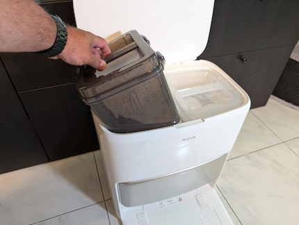 Het basisstation met de donkere vuilwatertank en de lichtgekleurde schoonwatertank.